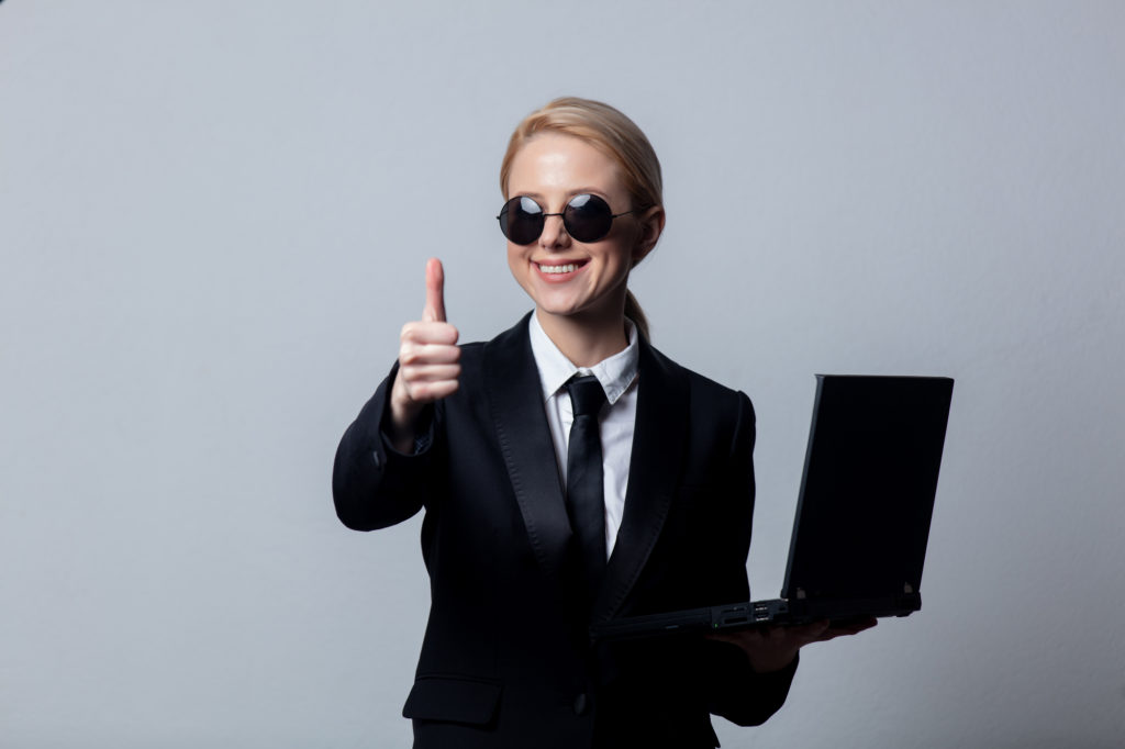 Style businesswoman in a classic black business suit and sunglasses with notebook computer